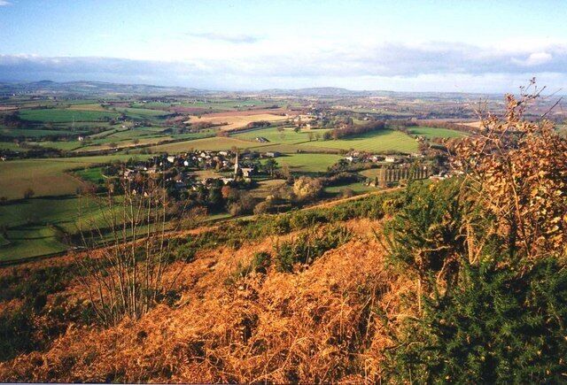 A rural landscape with rolling hills, a small village, and fields.