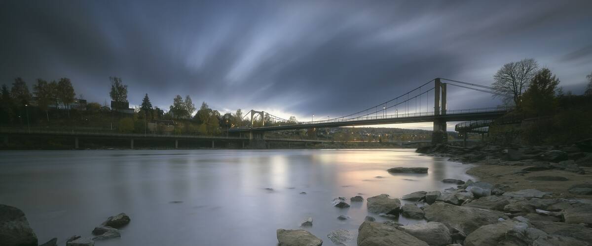 A river with rocks and a bridge in the background.
