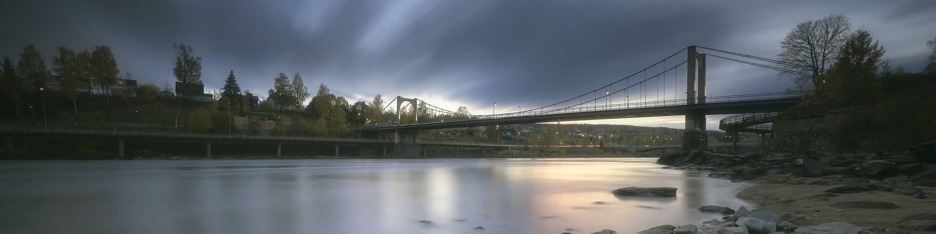 A river with rocks and a bridge in the background.