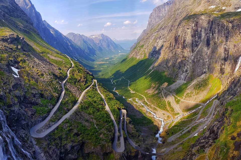 A mountain valley with winding roads and waterfalls.