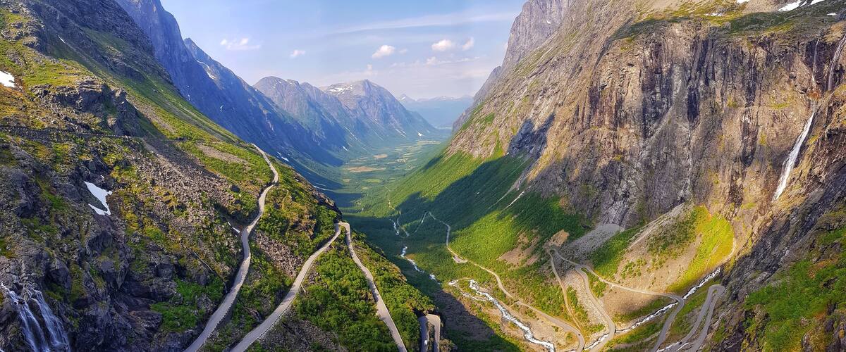 A mountain valley with winding roads and waterfalls.
