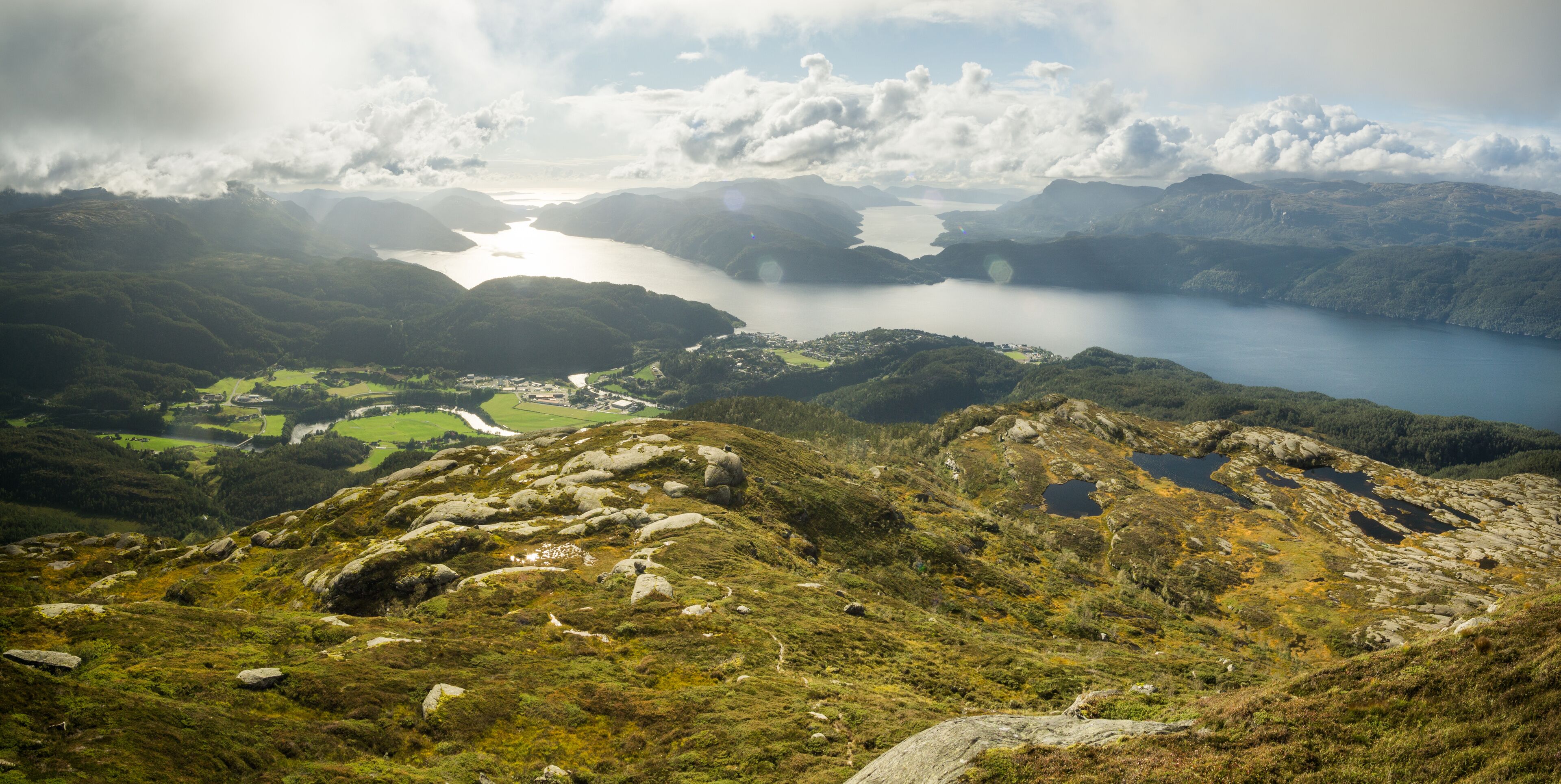 A mountainous landscape with a lake, rocky terrain, and a small village.