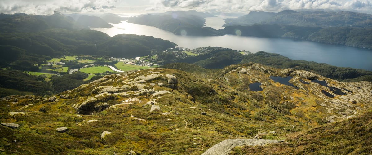 A mountainous landscape with a lake, rocky terrain, and a small village.