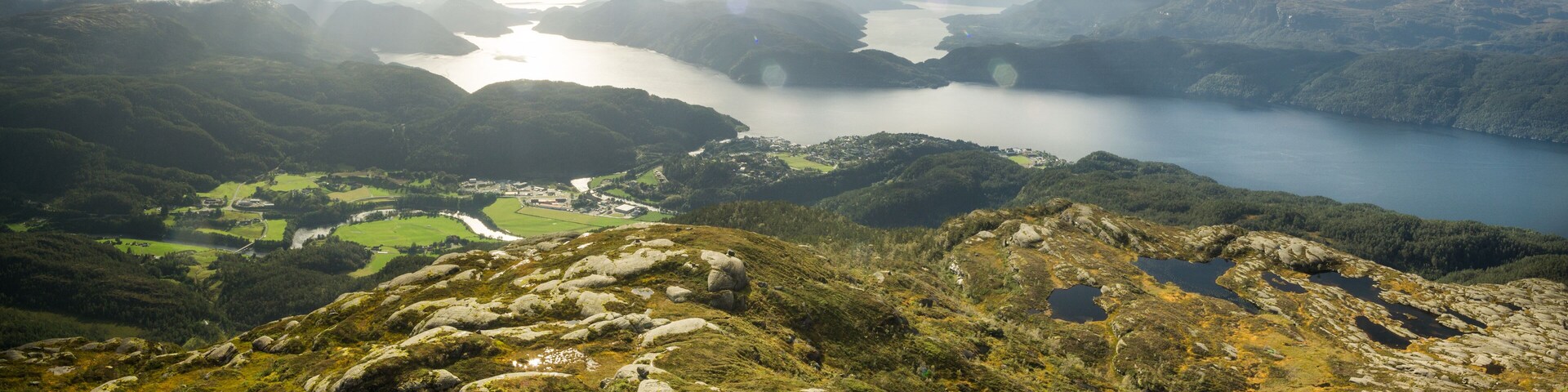 A mountainous landscape with a lake, rocky terrain, and a small village.