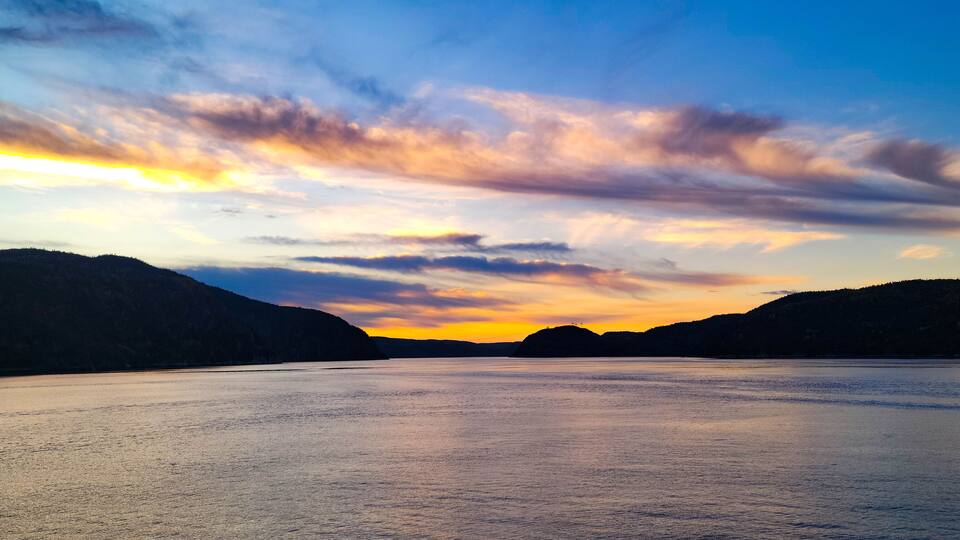 A river with mountains on either side and a sunset sky.
