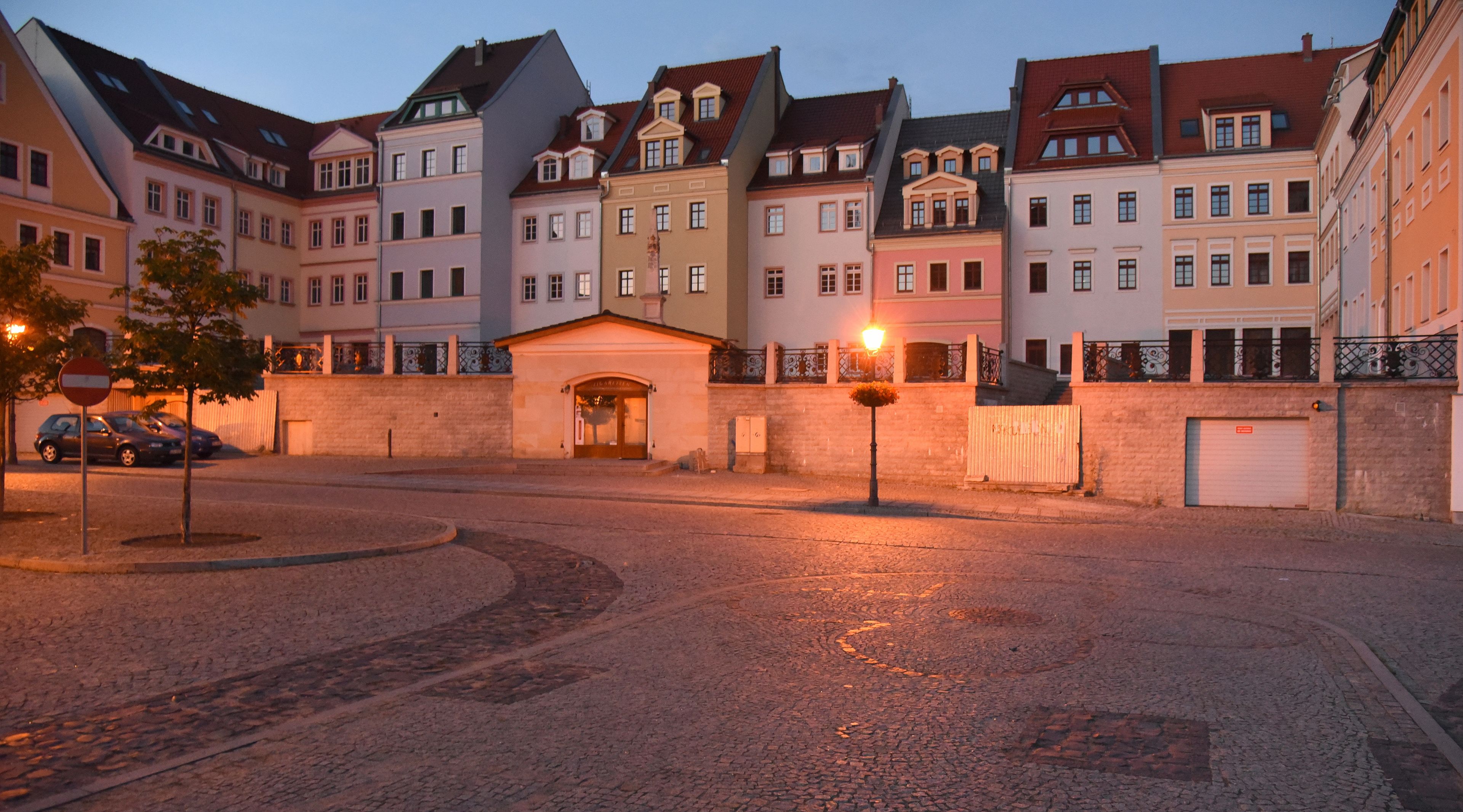 Gepflasterer Platz in Zgorzelec abendlich beleuchtet mit  Häuserzeile im Hintergrund 