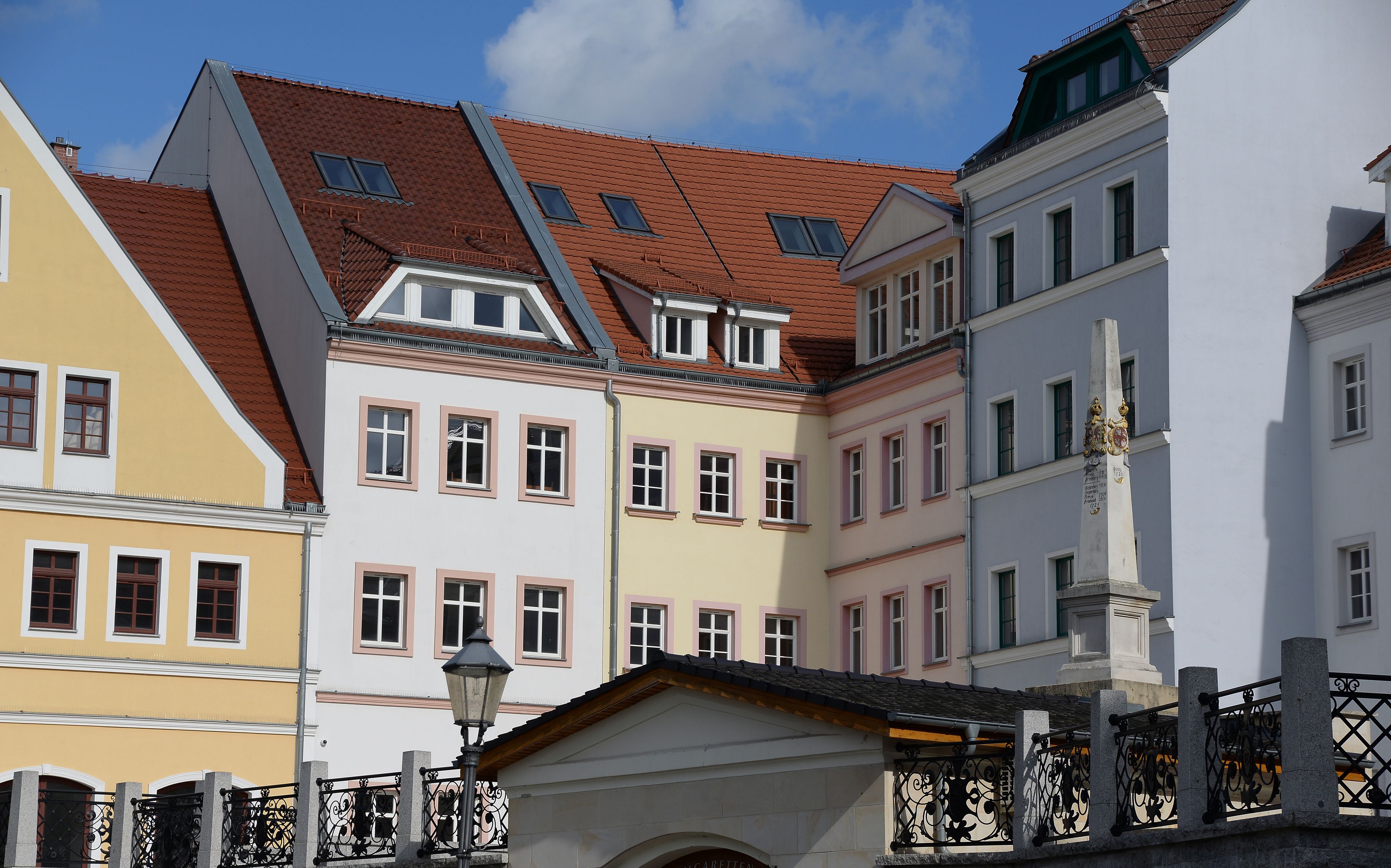 A row of colorful buildings with red-tiled roofs and a street lamp in the foreground.