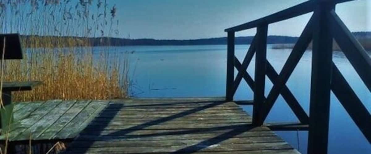 A wooden dock extending into calm water with a clear sky.