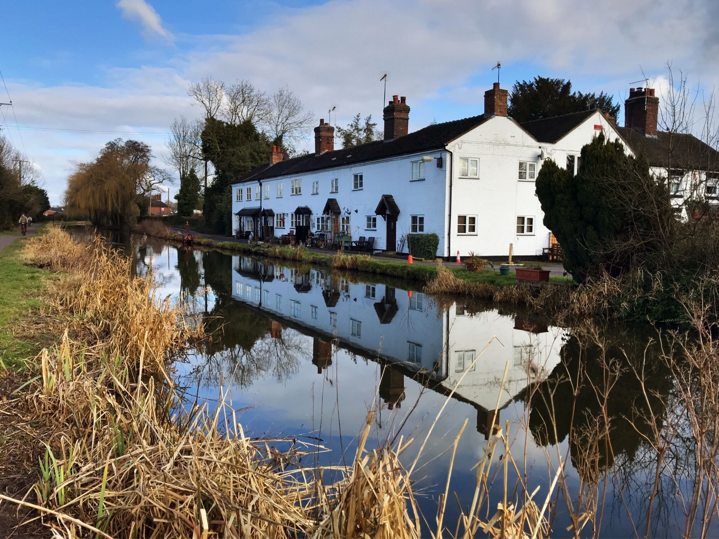 A riverside view with a white building, a canal, and surrounding vegetation.