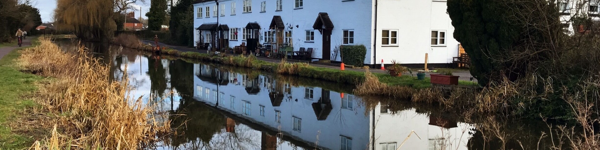 A riverside view with a white building, a canal, and surrounding vegetation.