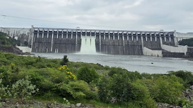 A large dam with water flowing over its spillway.