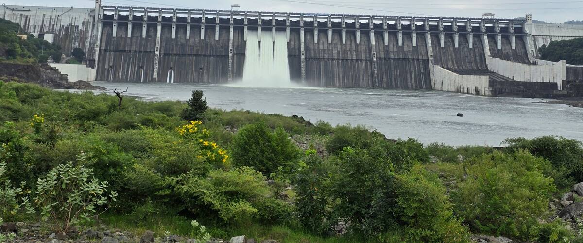 A large dam with water flowing over its spillway.
