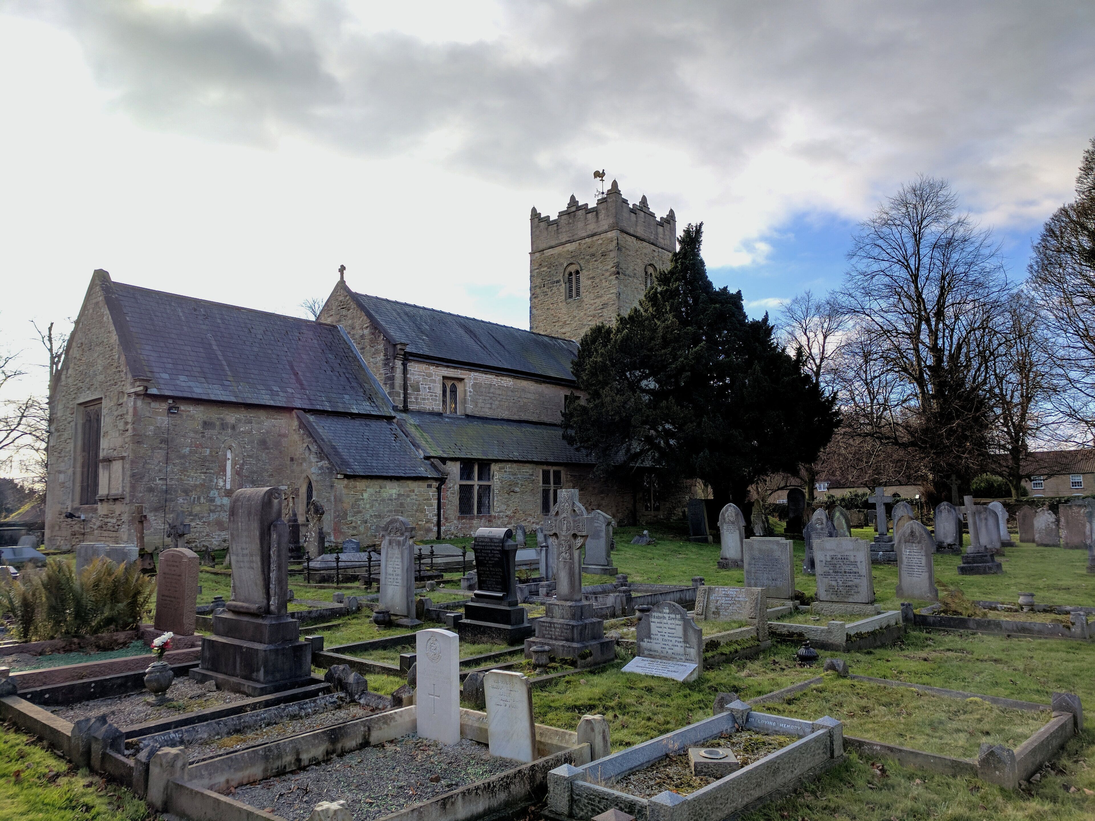 A cemetery with stone headstones and a church with a tower.