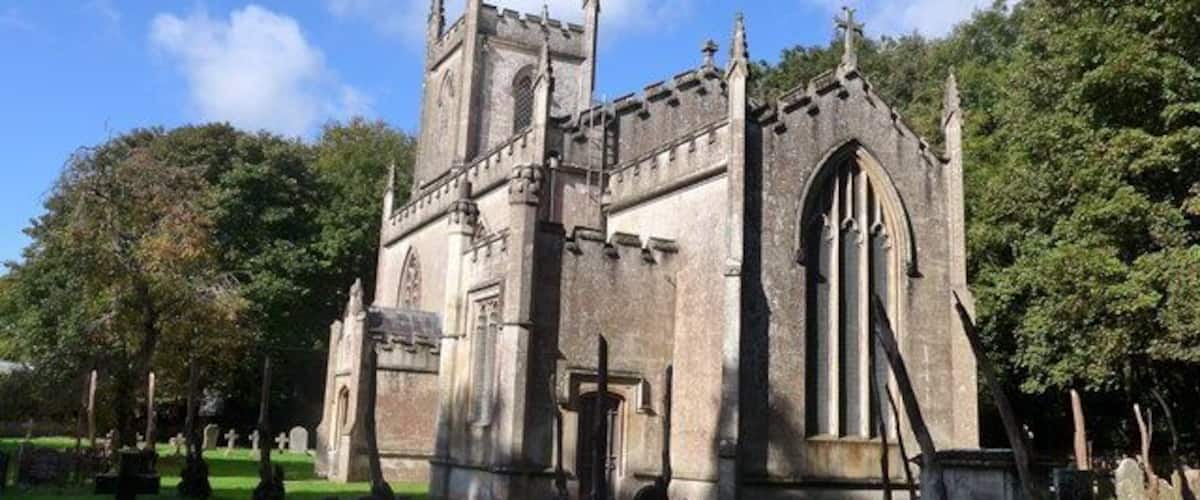 A historic church with a tall tower and arched windows, surrounded by a cemetery.