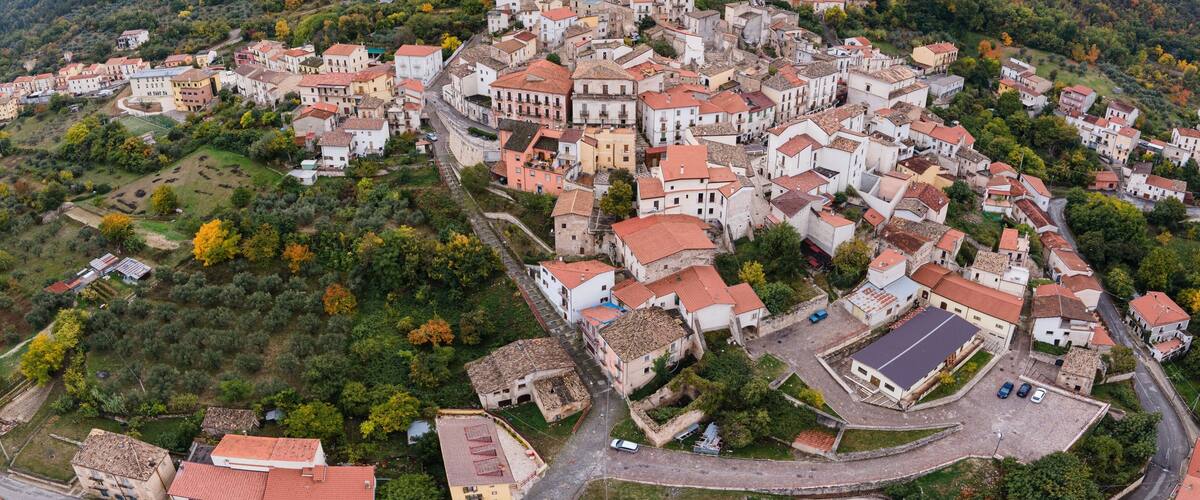An aerial view of a historic town nestled in a valley with a prominent mountain in the background.