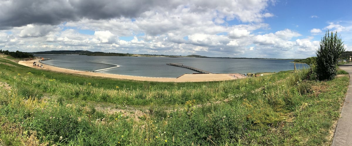 A large body of water with a sandy beach and a concrete structure in the middle.