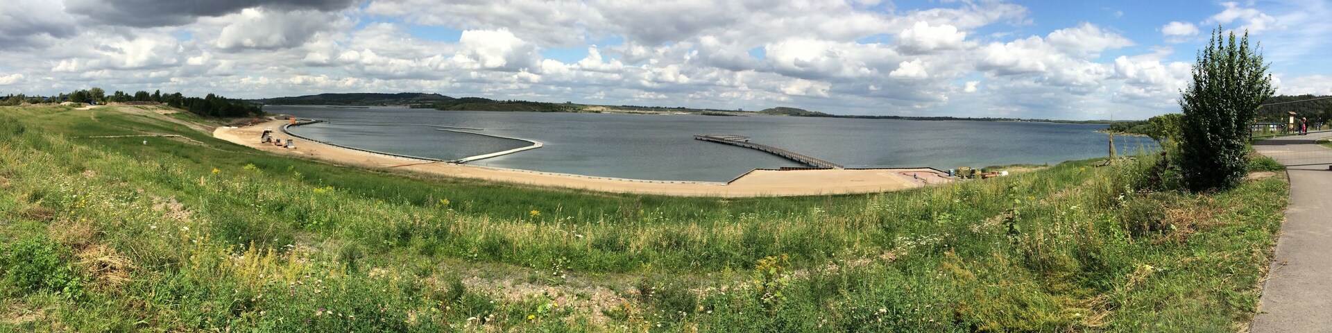 A large body of water with a sandy beach and a concrete structure in the middle.