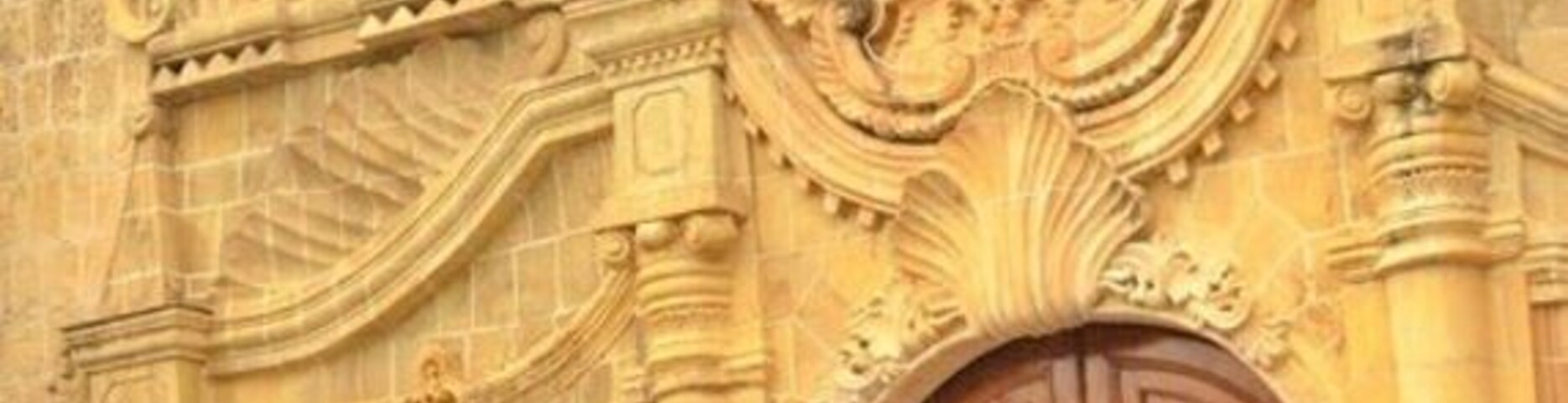 Un edificio histórico con elaboradas esculturas y una gran puerta de madera.