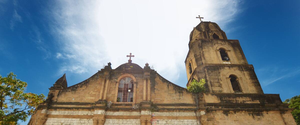 A historic church with a prominent bell tower, arched windows, and a large central doorway.