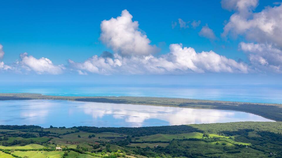 A coastal landscape with rolling hills, a large body of water, and a clear sky.
