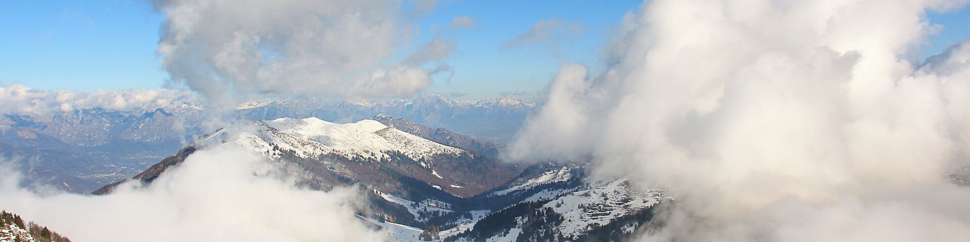 Cordilheira nevada com nuvens que cobrem parcialmente os picos.