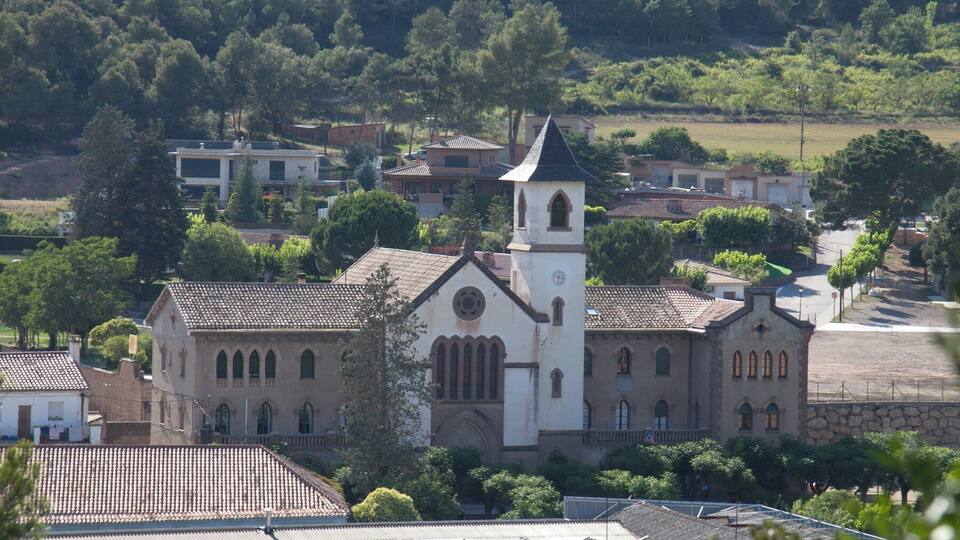 A church with a bell tower surrounded by residential buildings and trees.