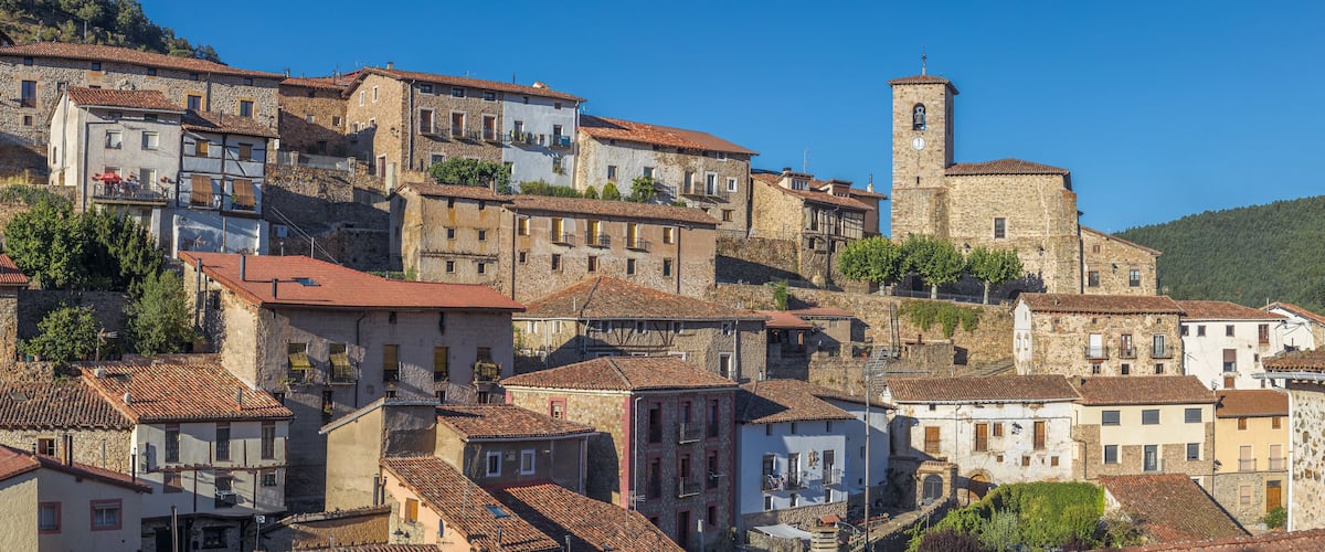 A historic town with stone buildings, a prominent clock tower, and terraced streets.