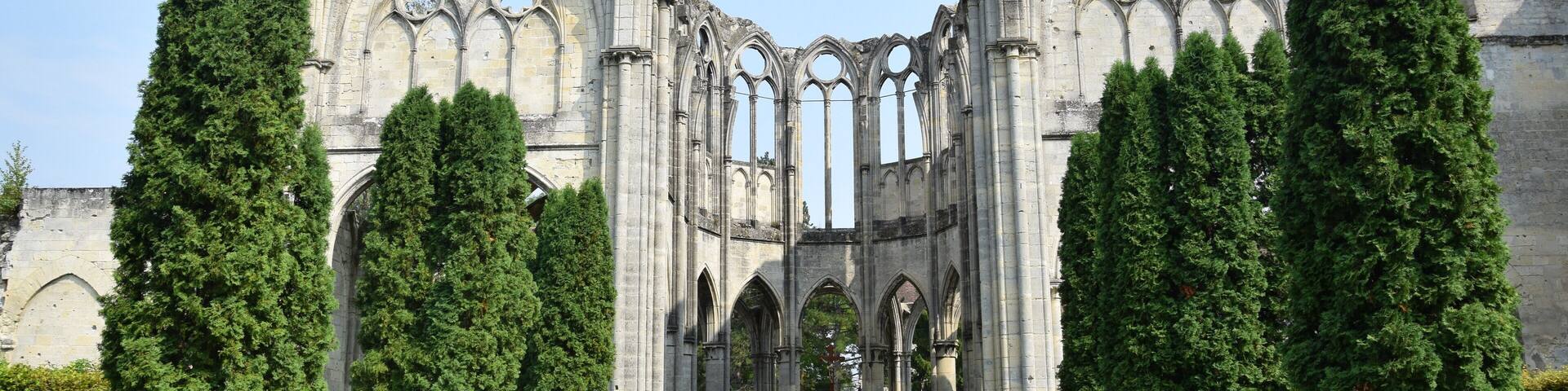 A Gothic cathedral with a large archway, surrounded by neatly trimmed evergreen trees.