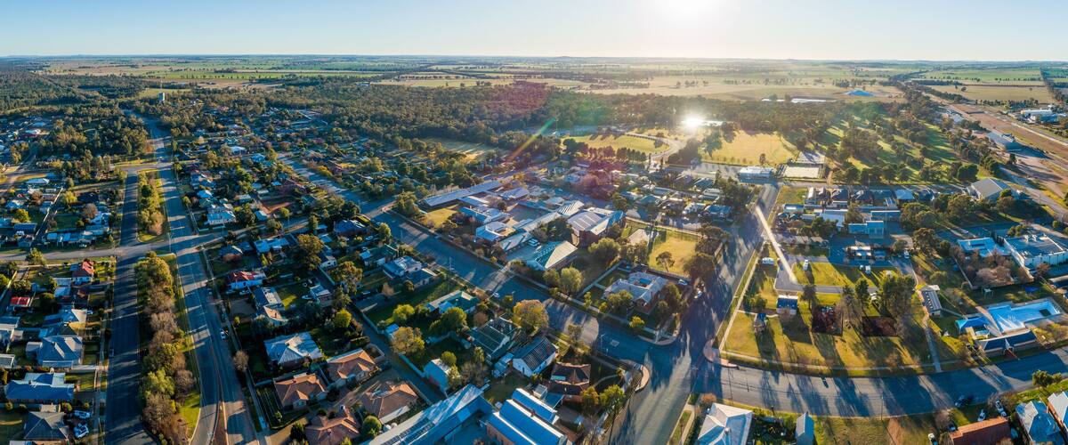 An aerial view of a suburban area with residential houses, roads, and green fields.