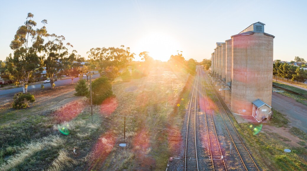 Golden sun flare over landscape aerial view of grain silos beside train line