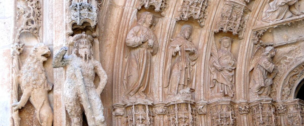 A detailed stone carving of religious figures and architectural elements on a cathedral wall.