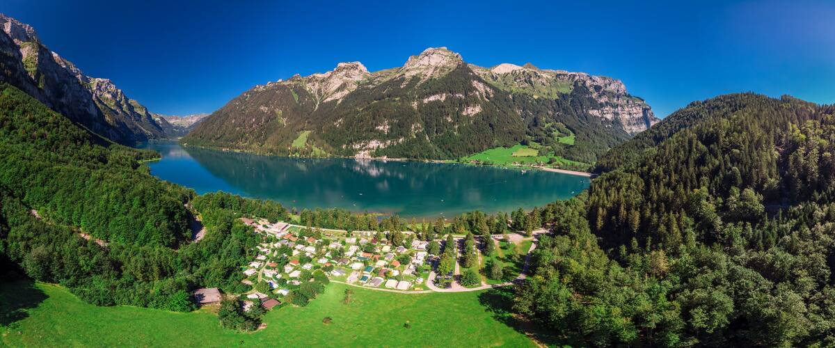 A lake surrounded by mountains, a forested area, and a small village.