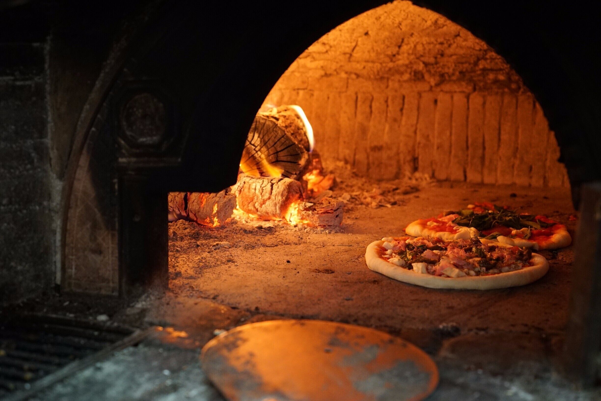 A brick oven with pizzas baking inside.