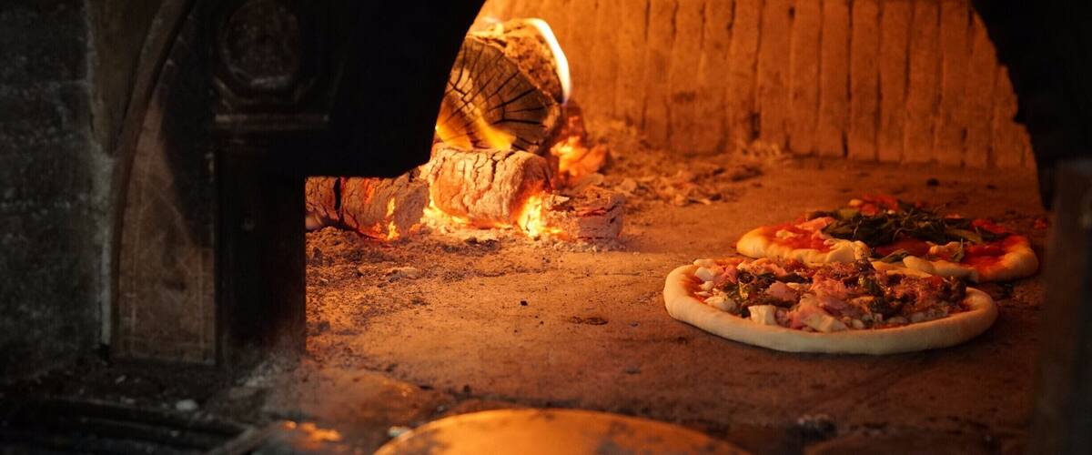 A brick oven with pizzas baking inside.