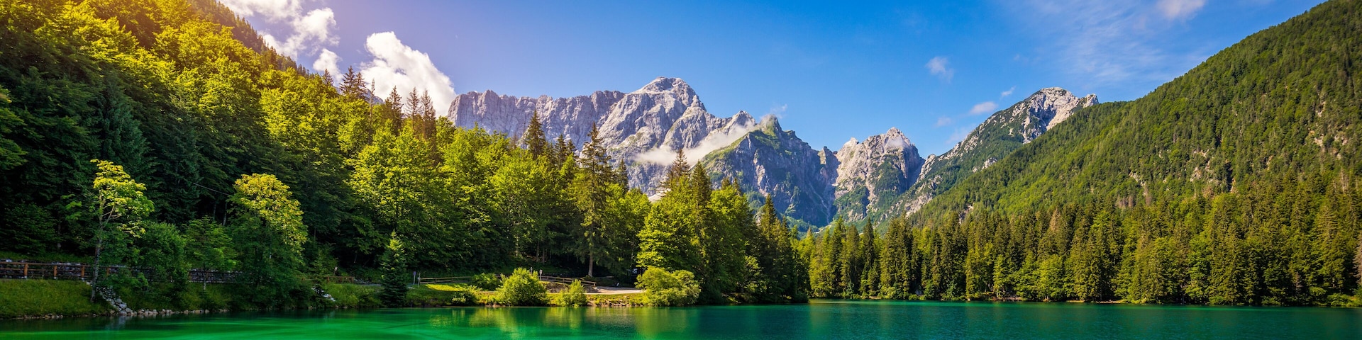 Um lago montanhoso rodeado por florestas densas e picos acidentados.