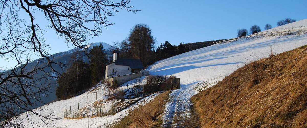 A snow-covered hill with a path leading to a white house.