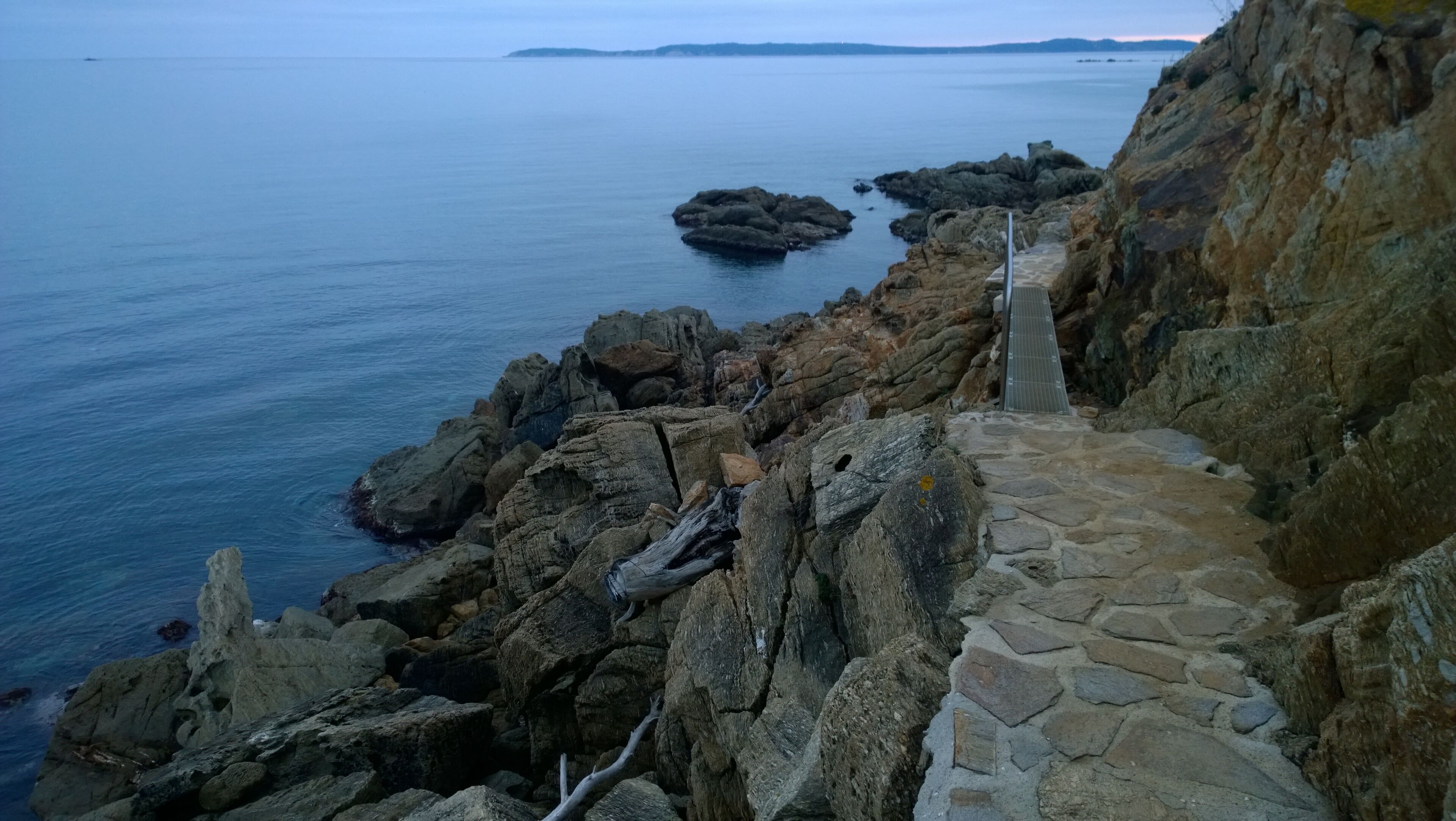 Un sentier côtier rocheux qui mène à un point de vue d’où l’on peut admirer la mer.