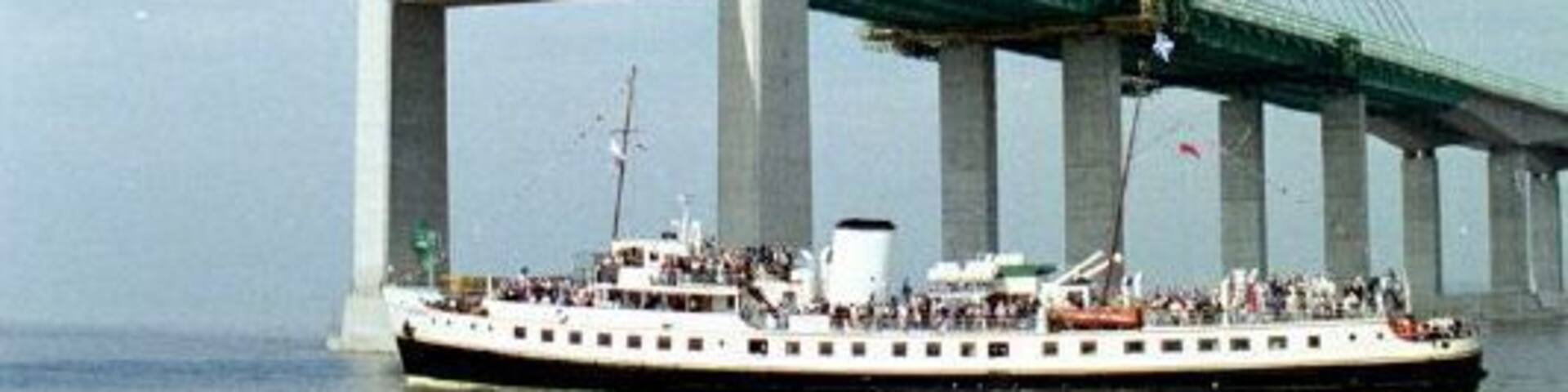 A large suspension bridge with a boat on the water below.