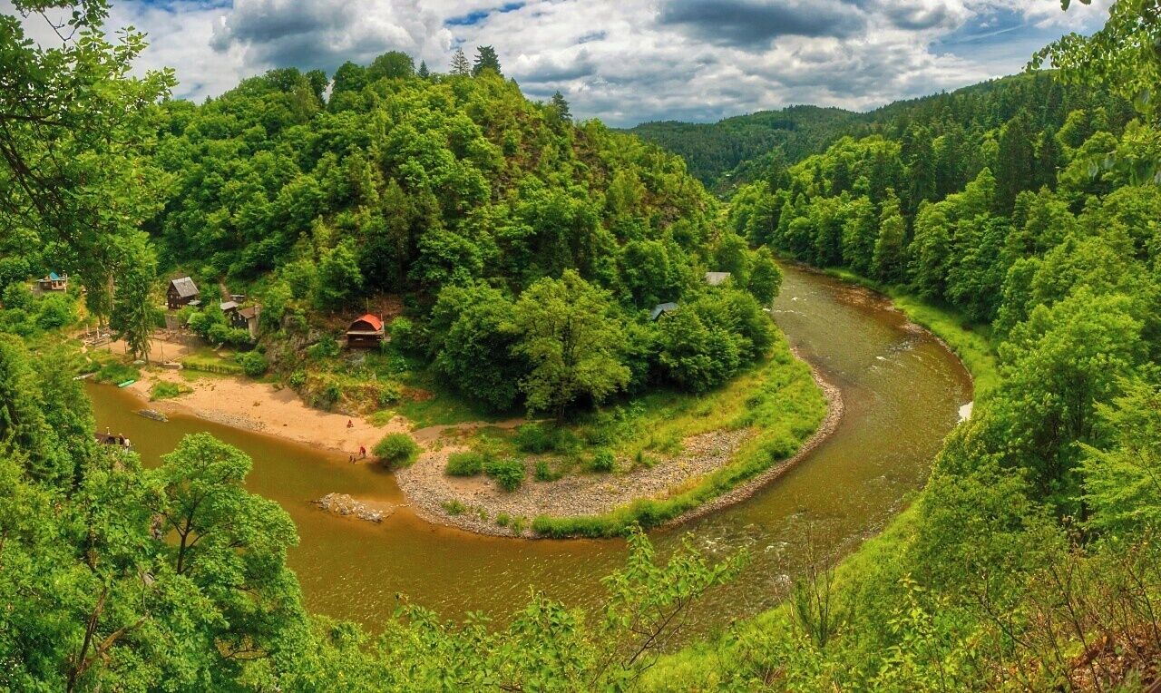 A river winding through a forested valley with houses on the banks.