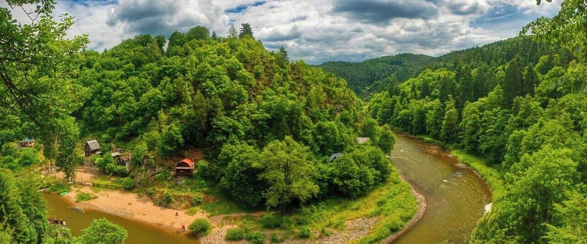 A river winding through a forested valley with houses on the banks.