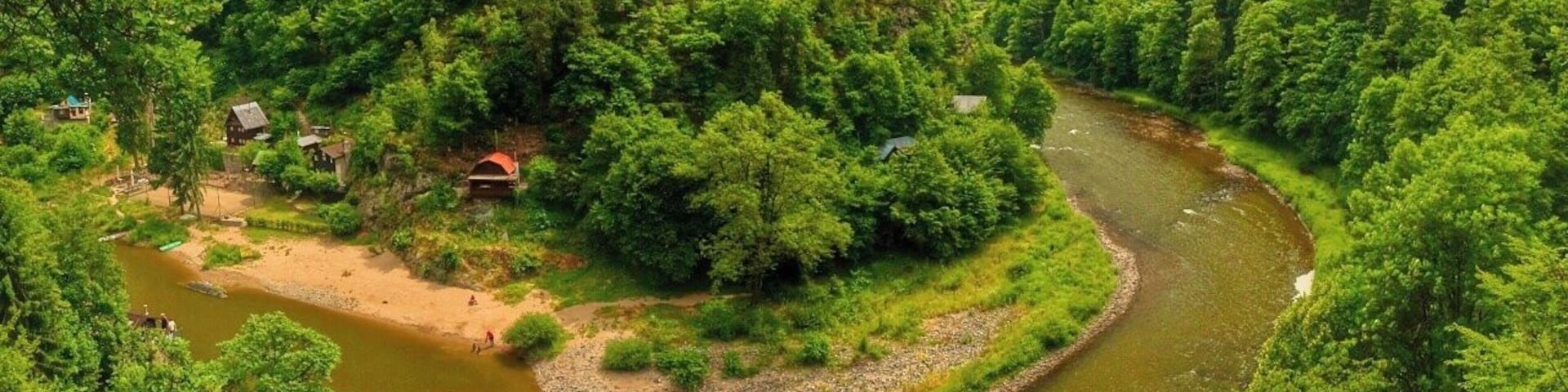 A river winding through a forested valley with houses on the banks.