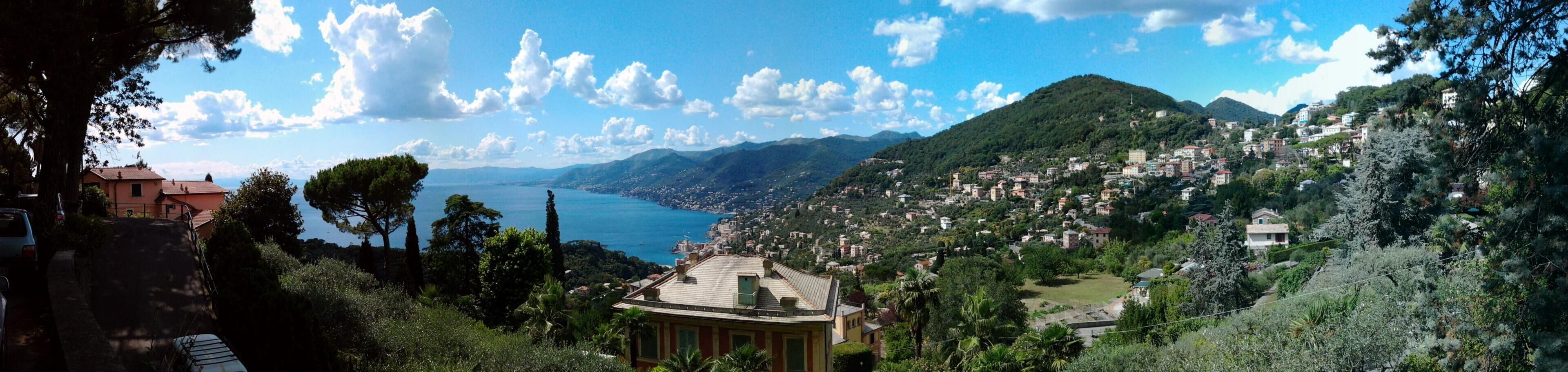 A coastal town with a prominent hill, a body of water, and lush greenery.