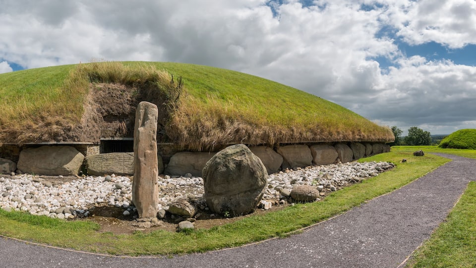 A thatched-roof structure surrounded by rocks and grass.