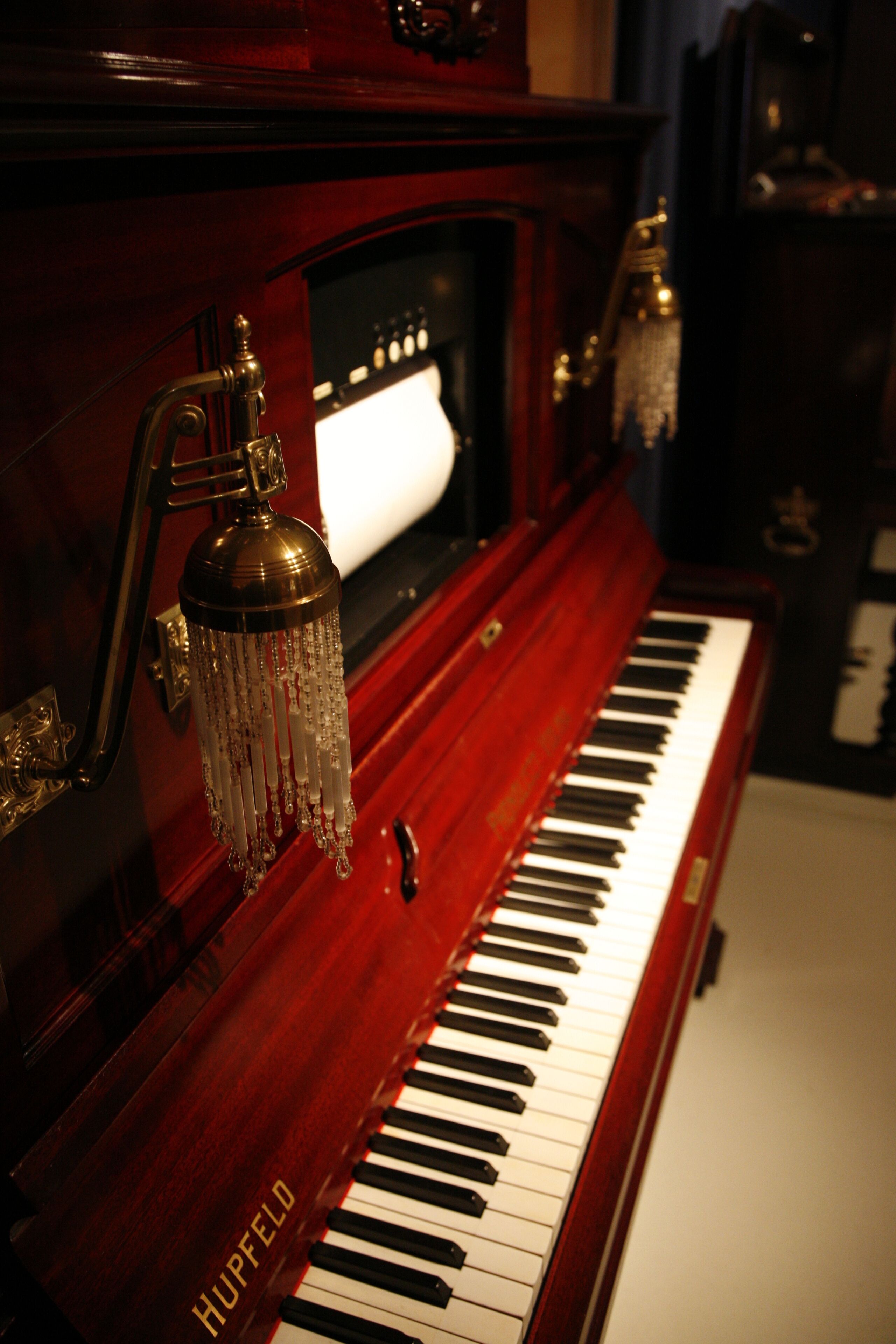 A grand piano with a polished wooden finish and a brand name "HUPFELD" on the side.