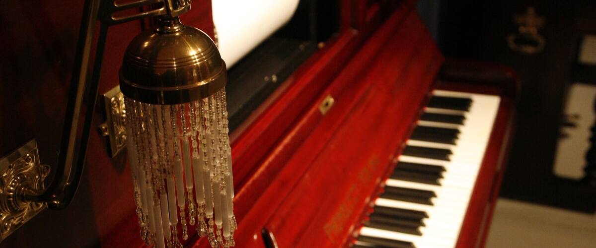 A grand piano with a polished wooden finish and a brand name "HUPFELD" on the side.