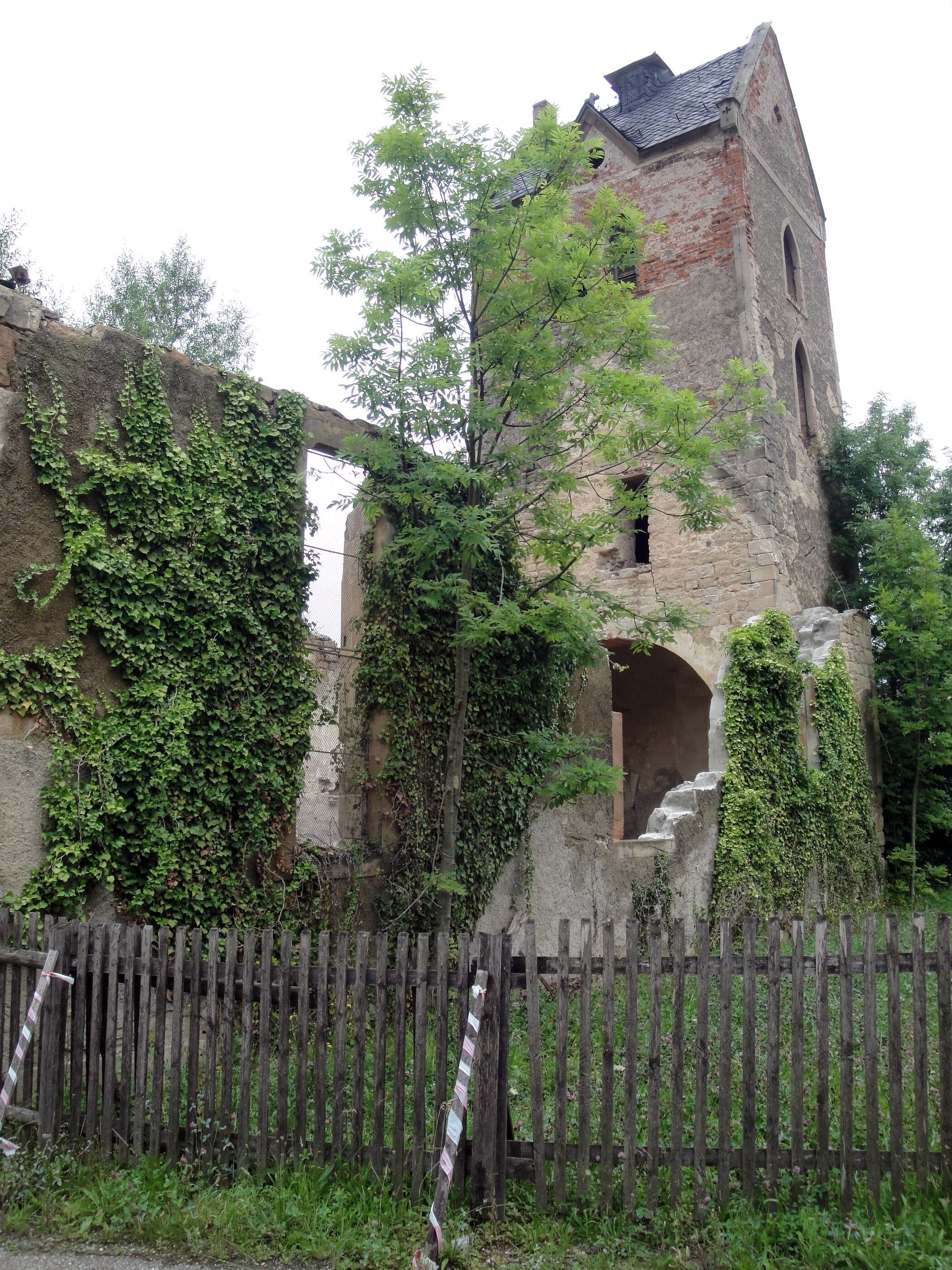 A historic stone tower with ivy-covered walls and a wooden fence in the foreground.