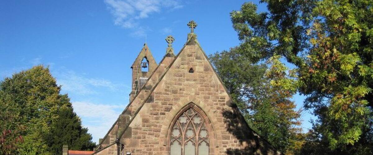 A stone church with a pointed roof and a large arched window.