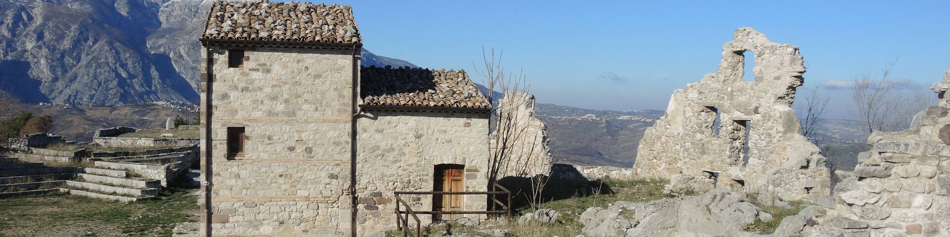Ancient stone ruins with a mountainous backdrop.