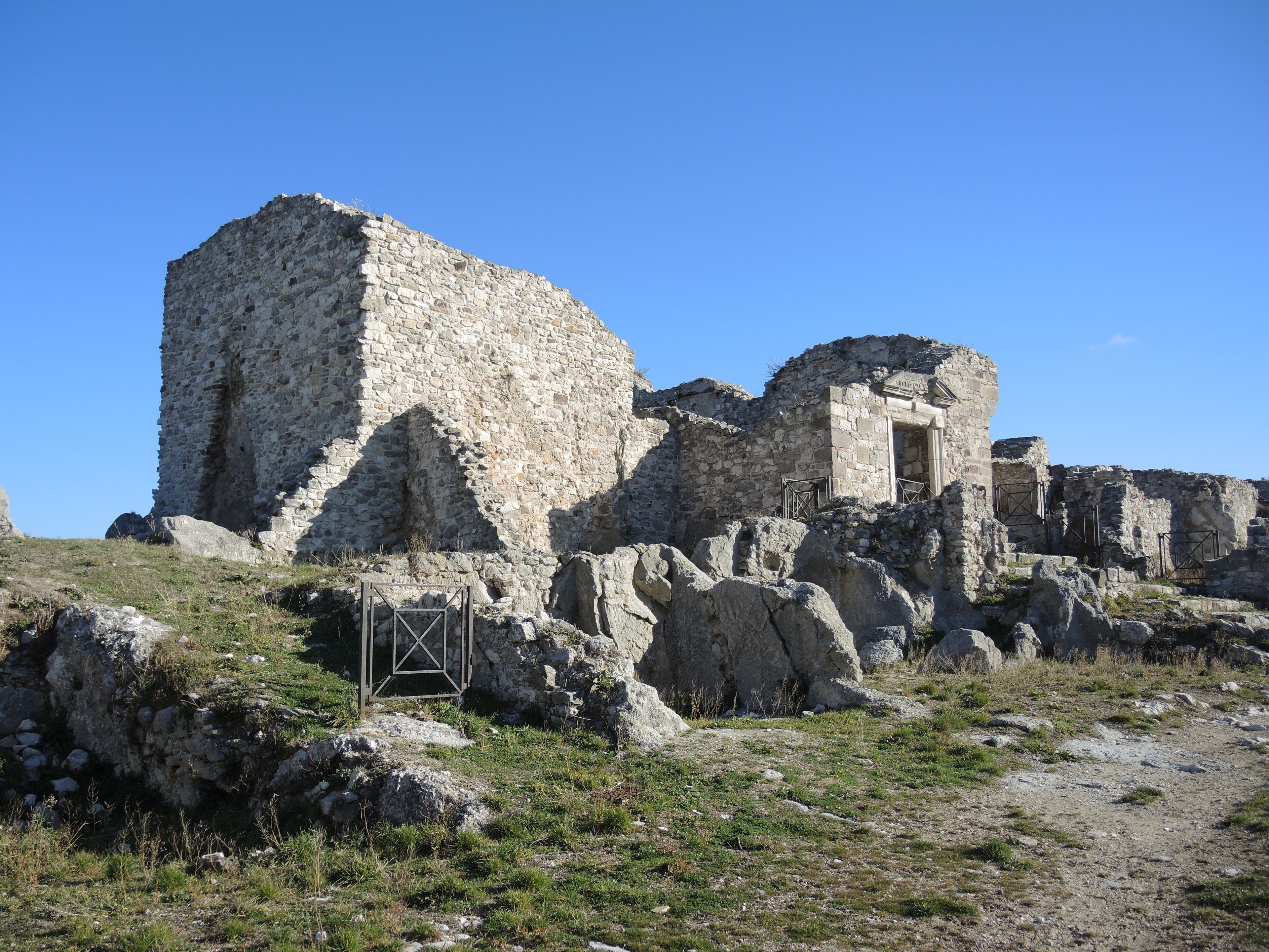 Ancient stone ruins with a large central structure and smaller surrounding buildings.