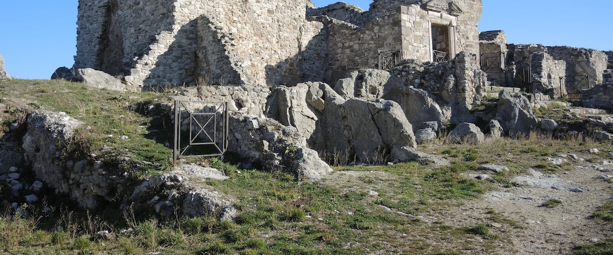 Ancient stone ruins with a large central structure and smaller surrounding buildings.